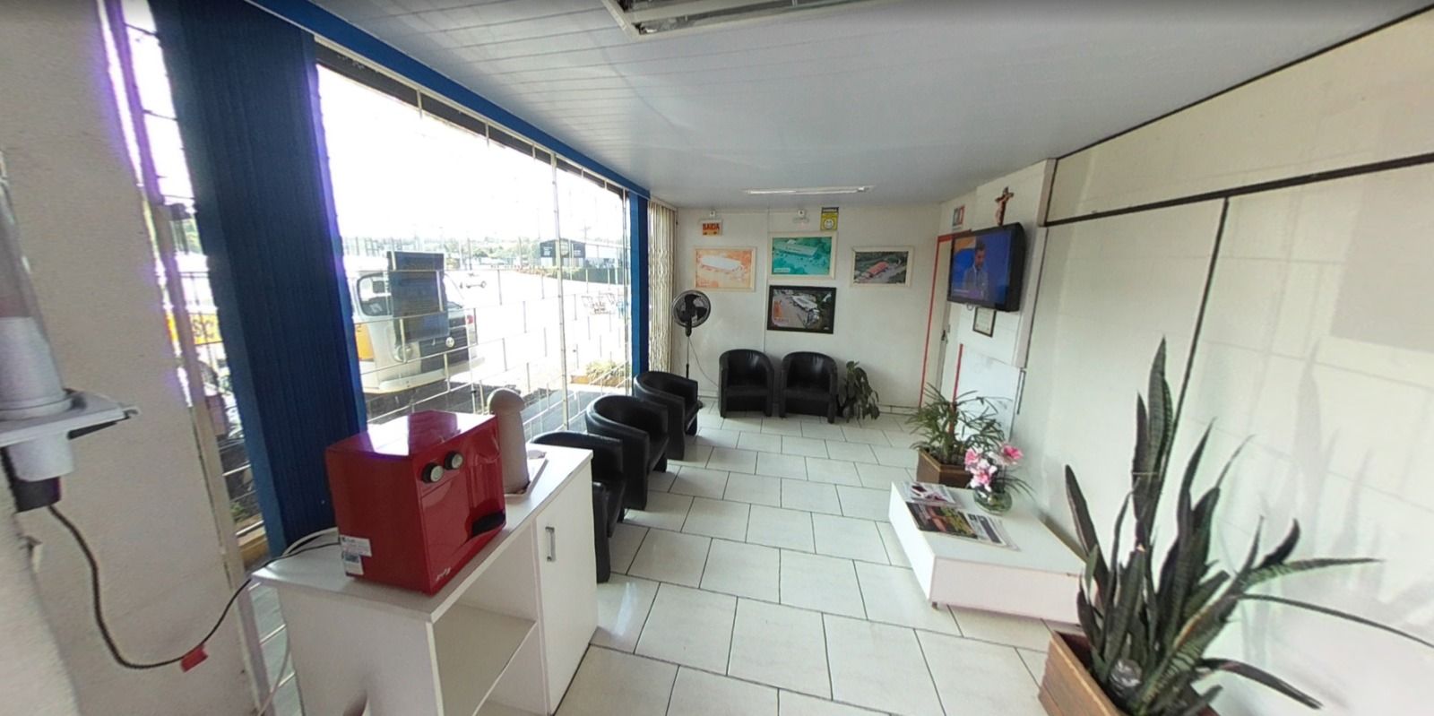 Sala de espera com poltronas, café e TV